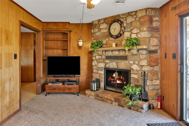 living room featuring light carpet, a stone fireplace, and wood walls