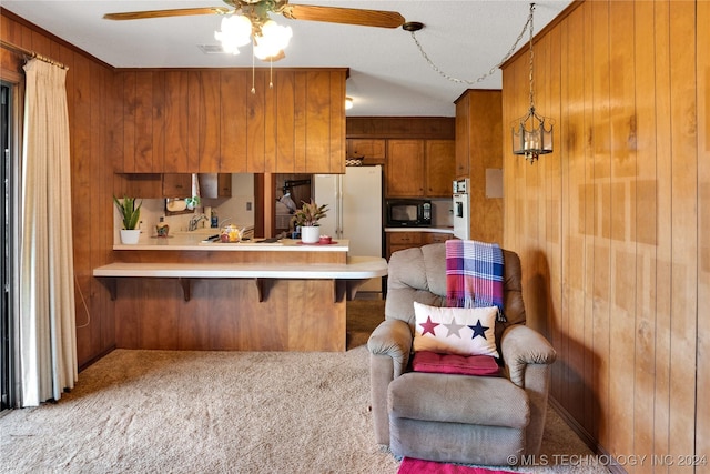 kitchen with wood walls, white appliances, ceiling fan, light colored carpet, and kitchen peninsula