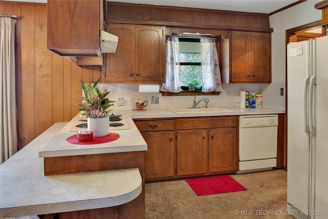 kitchen with wood walls, crown molding, white appliances, and sink