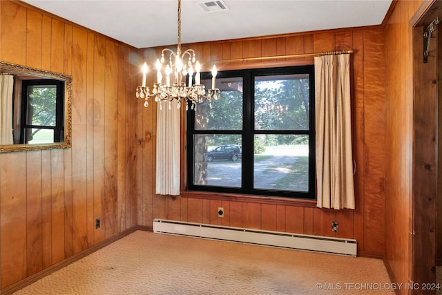 carpeted empty room featuring a chandelier, wood walls, and a baseboard radiator