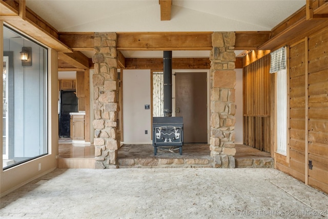 unfurnished living room featuring carpet flooring, vaulted ceiling, and a wood stove