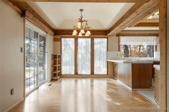 unfurnished dining area featuring a tray ceiling, light hardwood / wood-style flooring, and an inviting chandelier