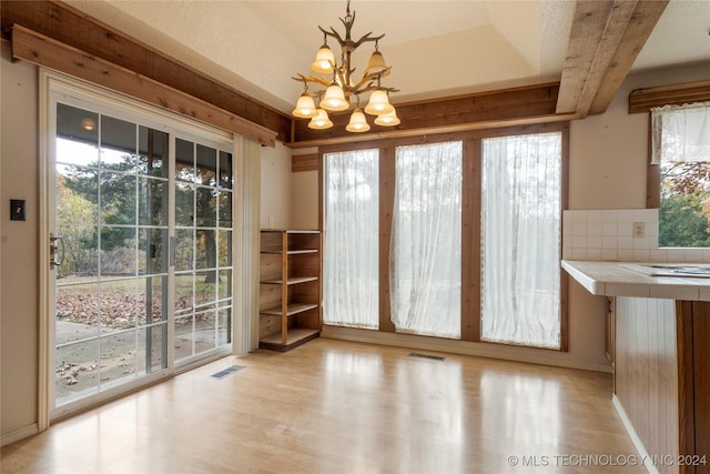 unfurnished dining area with a chandelier and light hardwood / wood-style floors