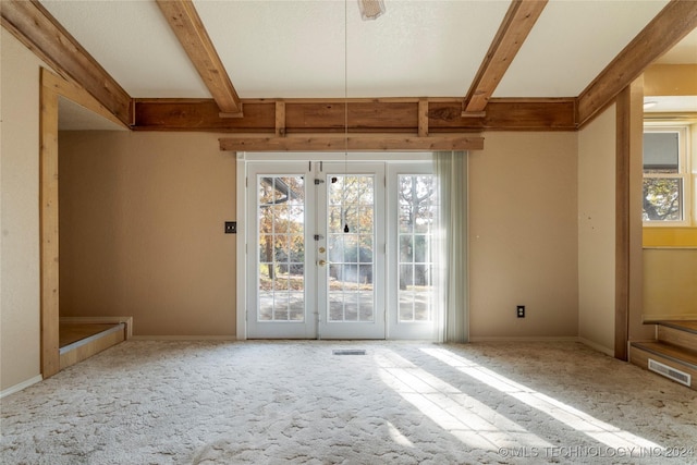 empty room featuring beam ceiling, carpet floors, and french doors