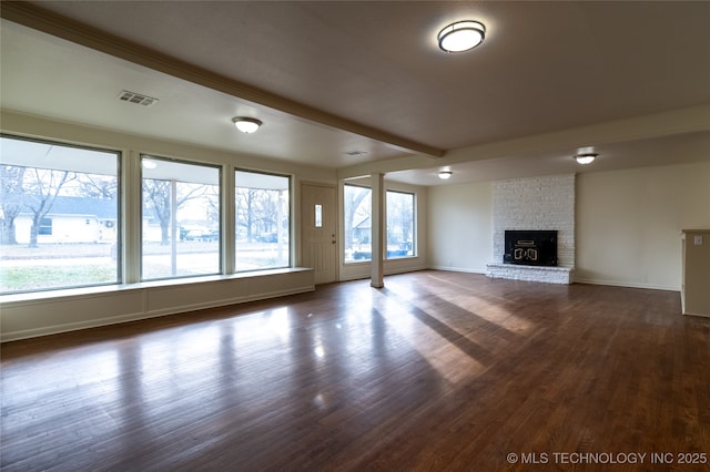 unfurnished living room featuring dark hardwood / wood-style flooring, beamed ceiling, and a brick fireplace