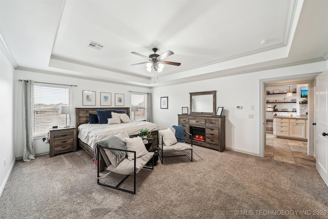 carpeted bedroom with ceiling fan, ornamental molding, and a tray ceiling