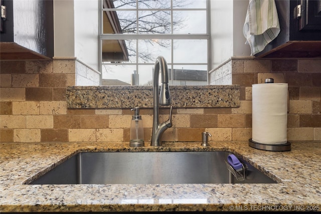 kitchen featuring light stone counters, sink, and tasteful backsplash