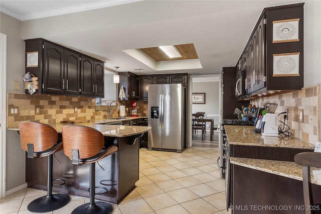 kitchen featuring sink, a breakfast bar area, decorative backsplash, light tile patterned flooring, and stainless steel appliances