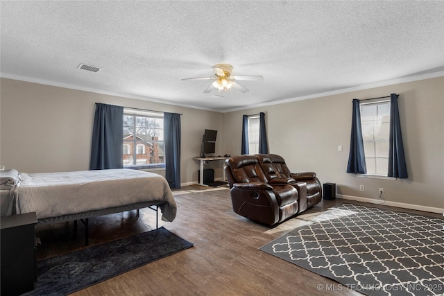 bedroom featuring ceiling fan, crown molding, wood-type flooring, and a textured ceiling