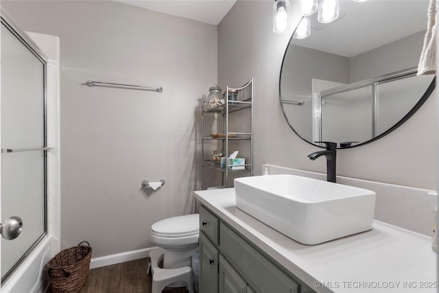 full bathroom with vanity, hardwood / wood-style flooring, toilet, enclosed tub / shower combo, and a textured ceiling