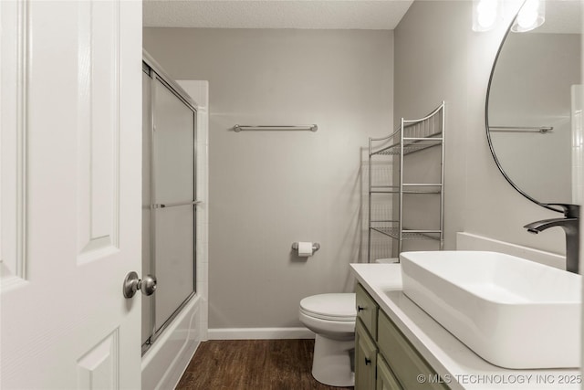 full bathroom with hardwood / wood-style flooring, enclosed tub / shower combo, vanity, toilet, and a textured ceiling