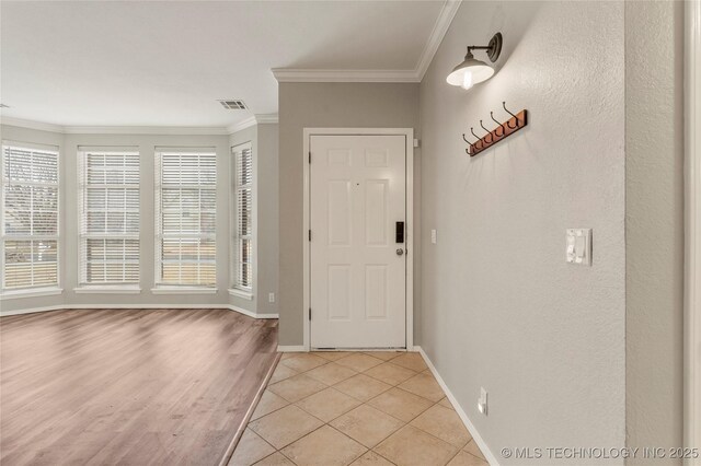 tiled entryway featuring crown molding