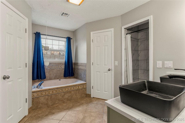 bathroom with tile patterned flooring, independent shower and bath, and a textured ceiling