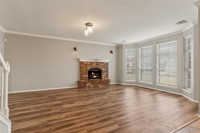 unfurnished living room featuring hardwood / wood-style flooring, ornamental molding, and a brick fireplace