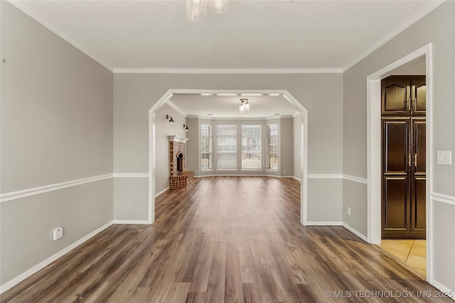 unfurnished living room featuring hardwood / wood-style floors, a fireplace, ornamental molding, and a textured ceiling