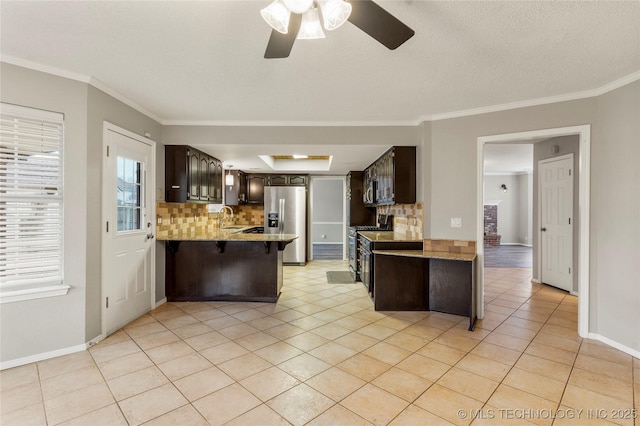 kitchen featuring sink, light tile patterned floors, dark brown cabinets, stainless steel appliances, and kitchen peninsula