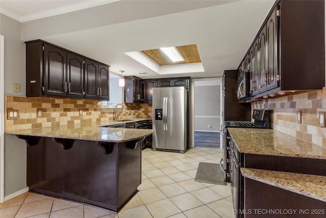 kitchen featuring sink, a breakfast bar area, light stone counters, kitchen peninsula, and stainless steel appliances