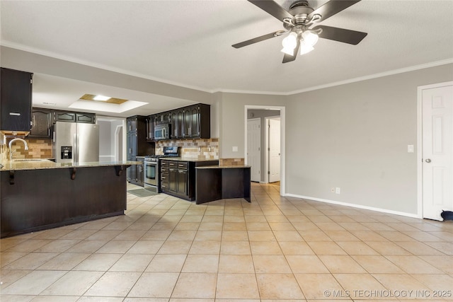 kitchen with light tile patterned floors, decorative backsplash, ornamental molding, and appliances with stainless steel finishes