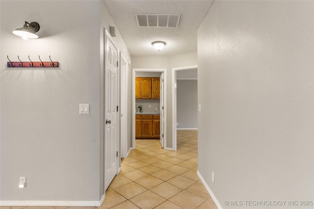 corridor with light tile patterned floors and a textured ceiling