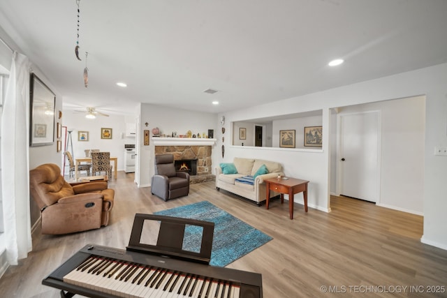 living room featuring a fireplace, hardwood / wood-style flooring, and ceiling fan