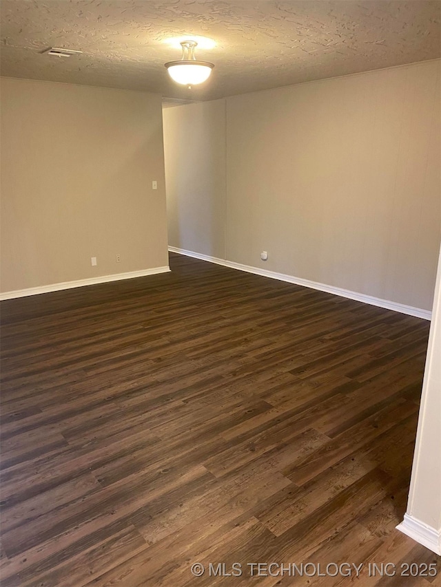 empty room with dark hardwood / wood-style flooring and a textured ceiling