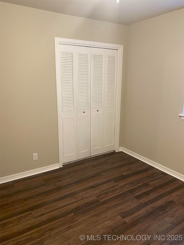 unfurnished bedroom with a closet and dark hardwood / wood-style floors