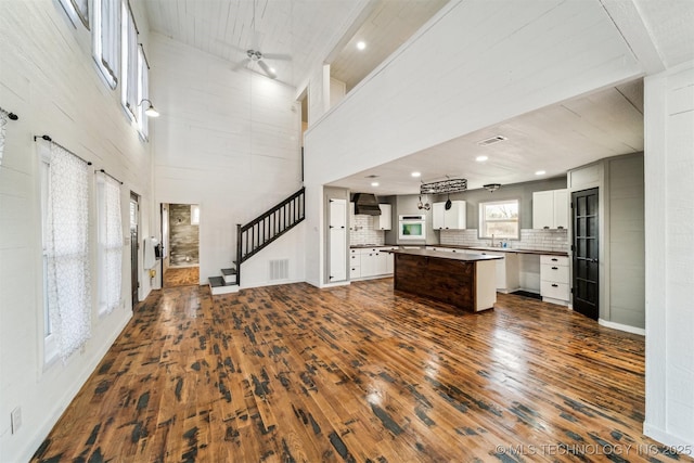 kitchen with a towering ceiling, wall oven, ceiling fan, white cabinets, and a center island