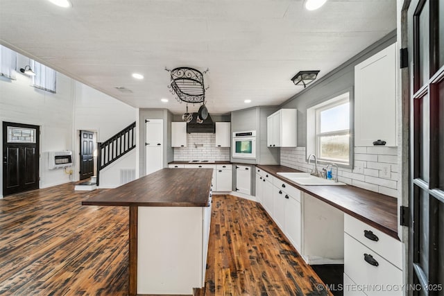 kitchen with wood counters, oven, sink, a kitchen island, and heating unit