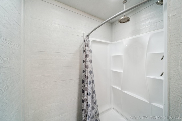 bathroom featuring wooden walls and walk in shower