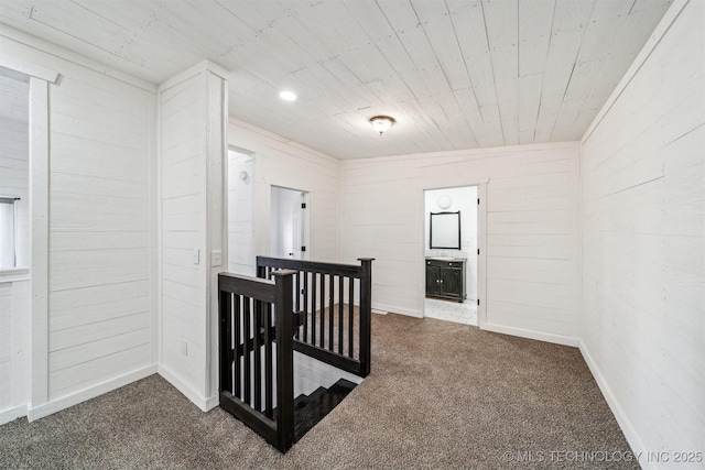 interior space featuring wooden walls and dark colored carpet