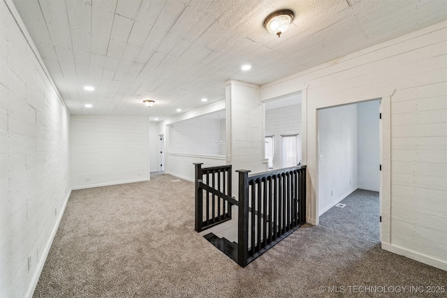 corridor featuring wooden walls and carpet