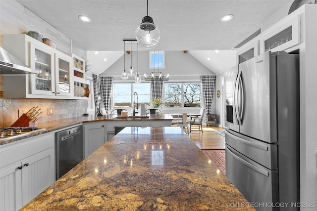 kitchen with appliances with stainless steel finishes, dark stone counters, pendant lighting, white cabinetry, and lofted ceiling