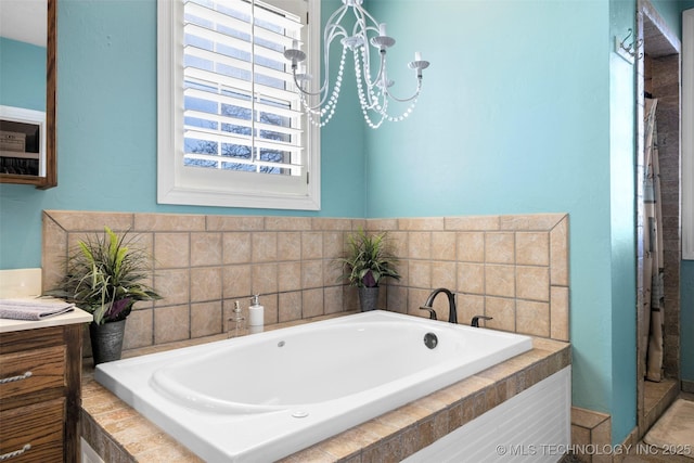 bathroom featuring a chandelier and tiled bath