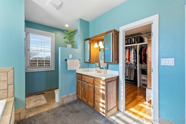 bathroom with hardwood / wood-style floors, vanity, and a washtub