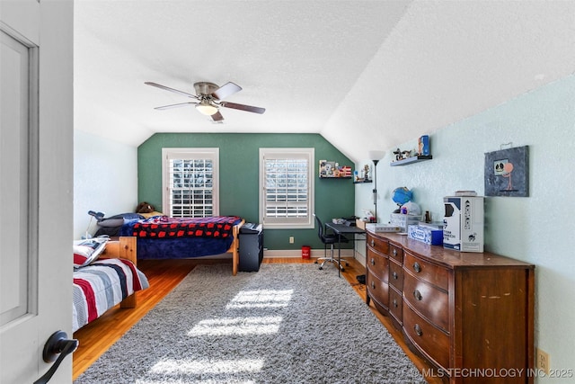 bedroom featuring a textured ceiling, ceiling fan, vaulted ceiling, and hardwood / wood-style flooring