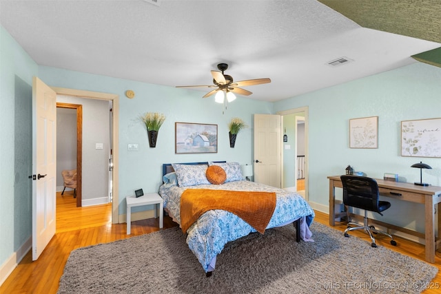 bedroom featuring a textured ceiling, light hardwood / wood-style floors, and ceiling fan