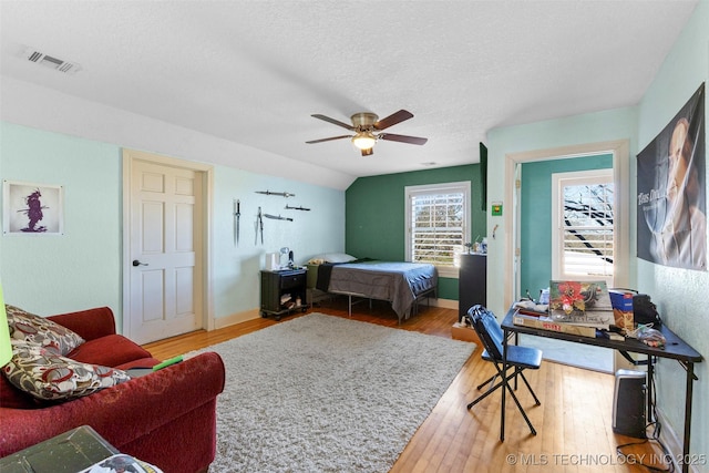 bedroom with a textured ceiling, ceiling fan, wood-type flooring, and lofted ceiling