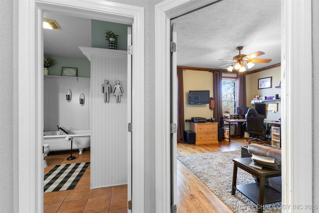 hallway with light tile patterned floors, a textured ceiling, and ornamental molding