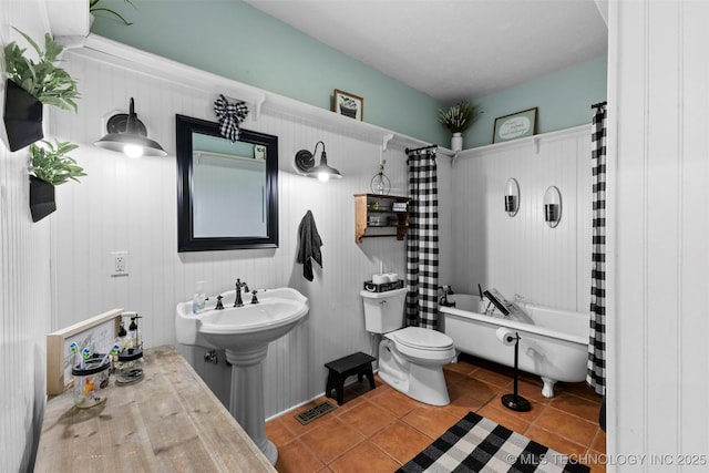 bathroom with toilet, tile patterned floors, wood walls, and shower / tub combo with curtain