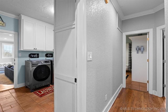 laundry room featuring washer and clothes dryer, cabinets, crown molding, a textured ceiling, and light hardwood / wood-style floors