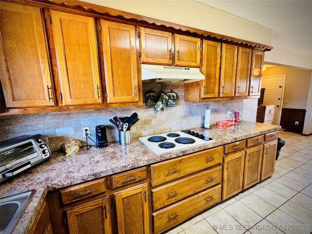 kitchen featuring light stone countertops, tasteful backsplash, sink, white electric cooktop, and light tile patterned flooring