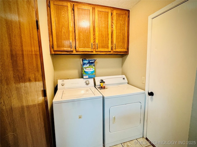 clothes washing area with light tile patterned floors, separate washer and dryer, a textured ceiling, and cabinets