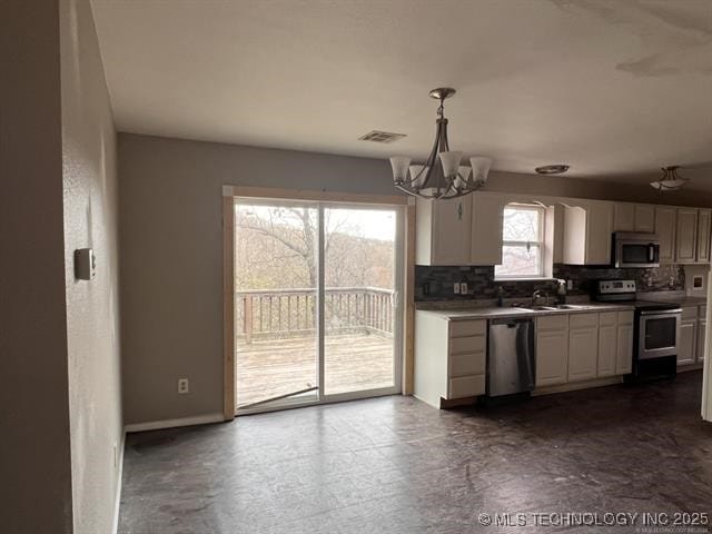 kitchen with white cabinets, hanging light fixtures, decorative backsplash, a notable chandelier, and stainless steel appliances