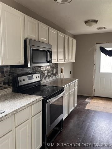 kitchen featuring backsplash, white cabinetry, dark wood-type flooring, and appliances with stainless steel finishes