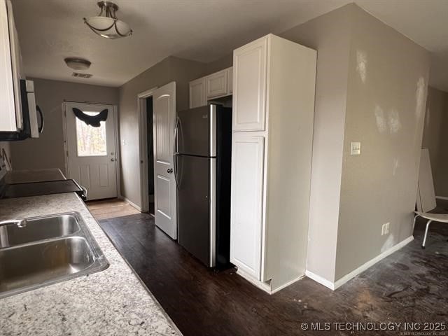 kitchen with white cabinetry, sink, dark hardwood / wood-style floors, stainless steel fridge, and stove