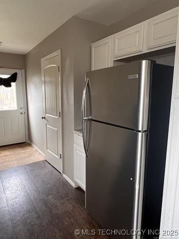 kitchen with hardwood / wood-style floors, white cabinetry, and stainless steel refrigerator