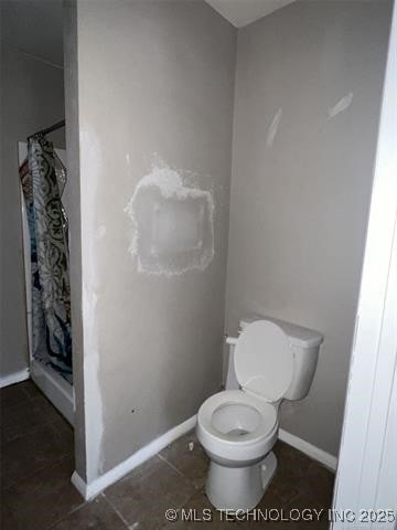 bathroom with tile patterned flooring, a shower with curtain, and toilet