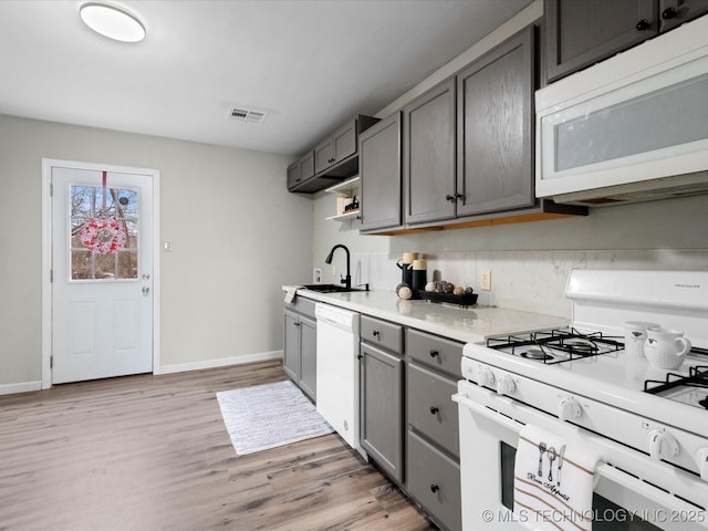 kitchen featuring light hardwood / wood-style floors, gray cabinets, white appliances, and sink