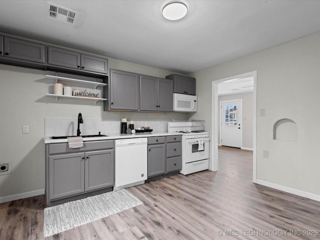 kitchen featuring white appliances, light hardwood / wood-style flooring, gray cabinetry, and sink