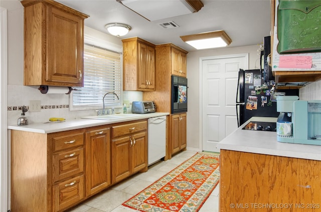 kitchen with tasteful backsplash, sink, light tile patterned flooring, and black appliances